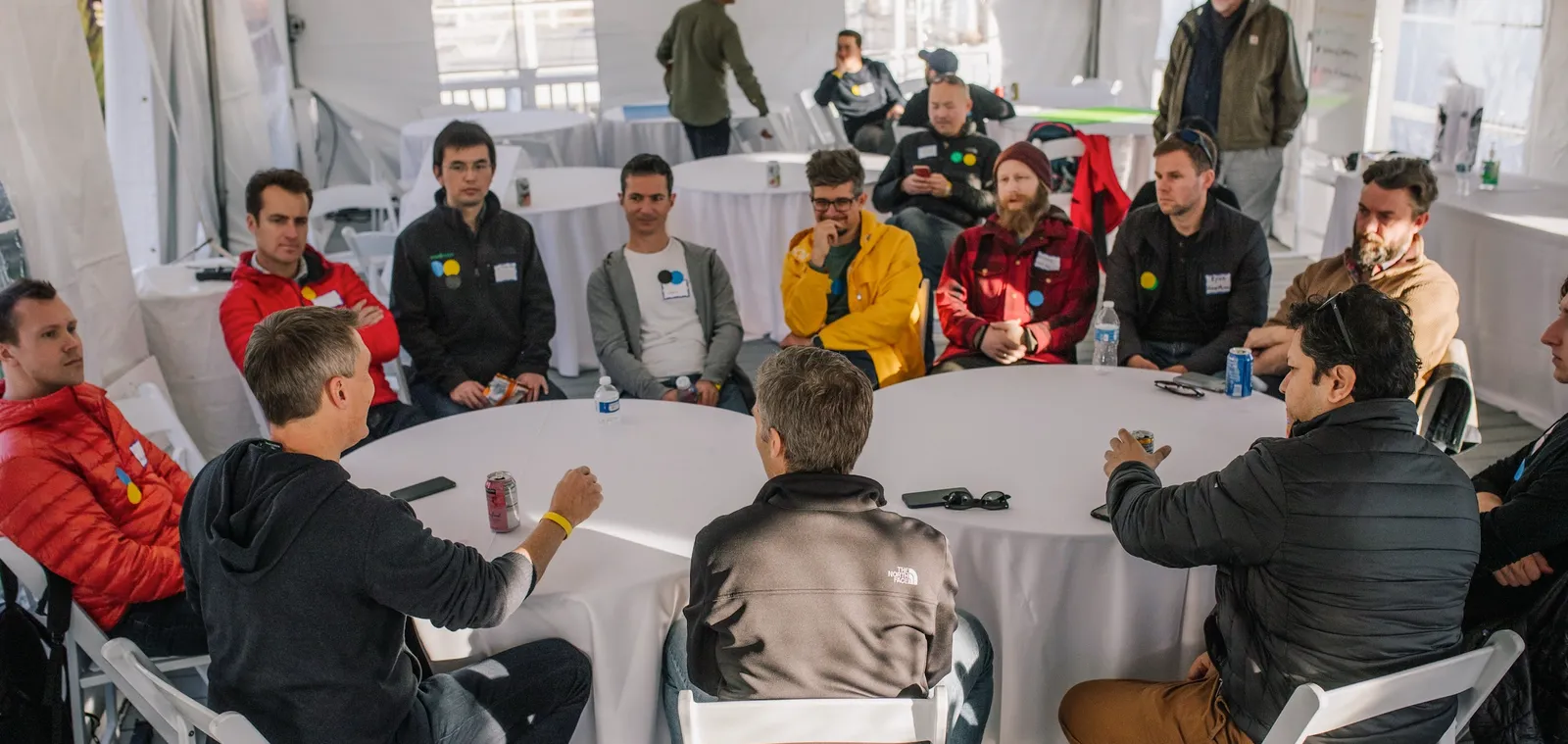A large, well-attended session at a round table under a tent, with many founders leaning in to listen.